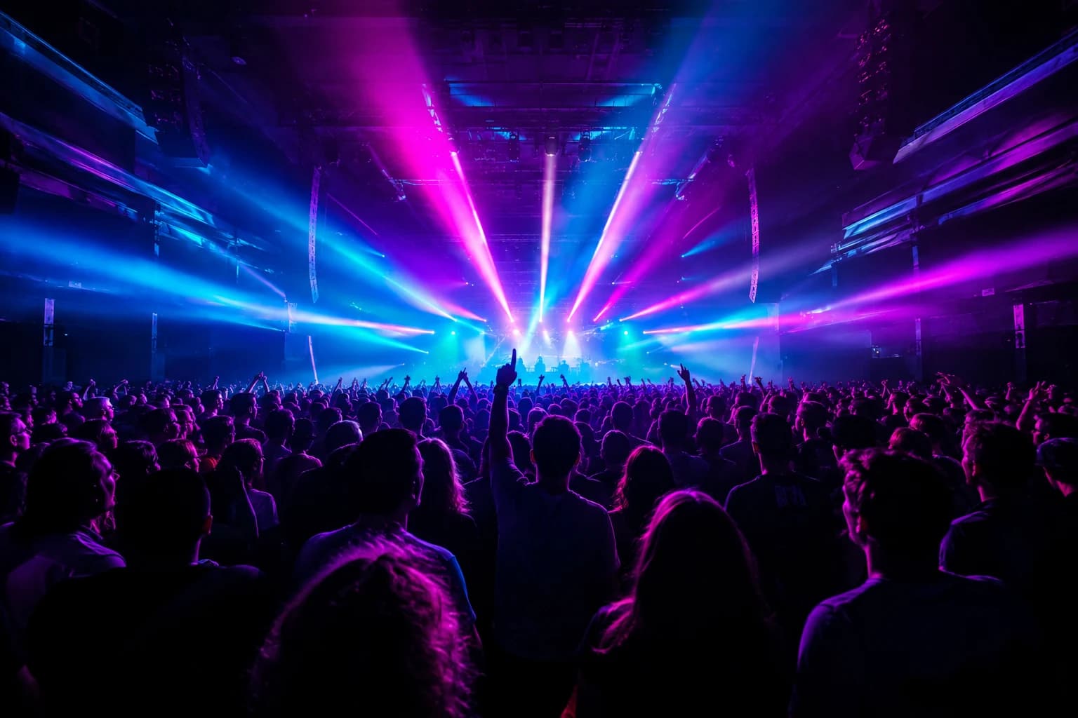 A concert crowd beneath brilliant spectral stage beams